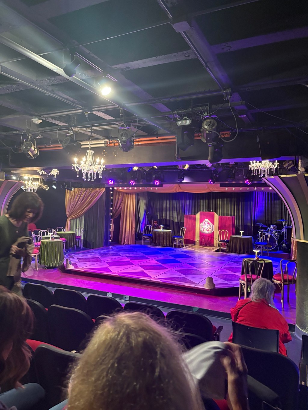 Small, intimate Circle Theatre stage with purple lighting, chandeliers and cabaret-style tables in downtown Fort Worth